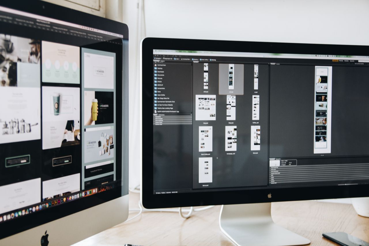 Un espace de travail moderne avec deux écrans d'ordinateur affichant des projets de conception web, mettant en avant la technologie et la productivité.